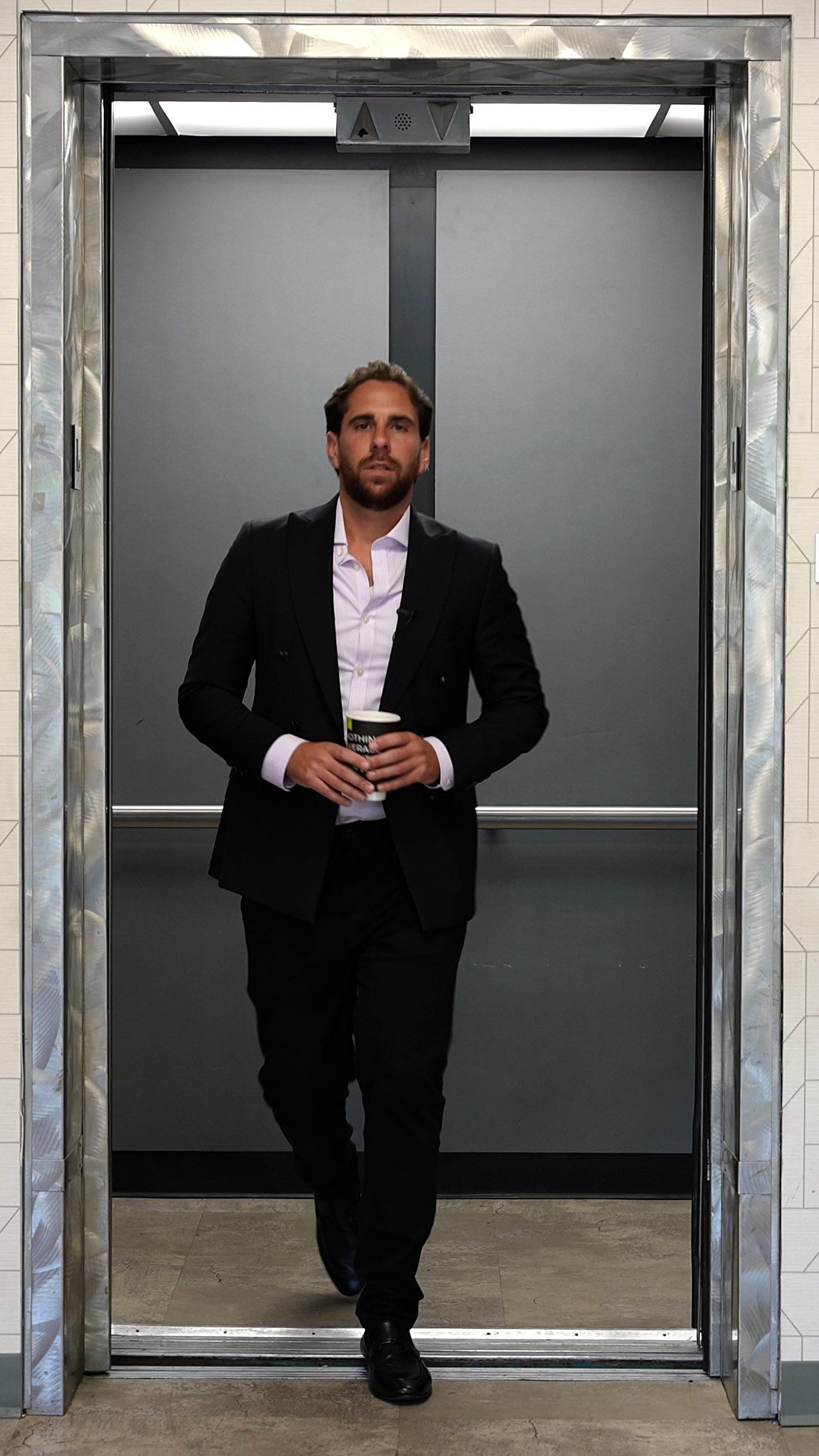 Shlomo Yachnes stepping out of an office elevator, coffee in hand